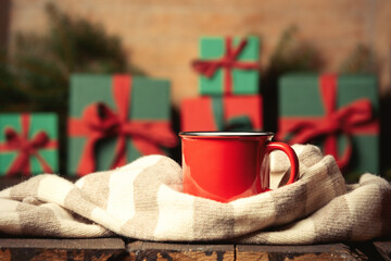 Cup of coffee and scarf next to gifts on wooden table