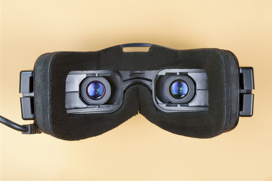 Black virtual reality glasses with blue lenses isolated on beige