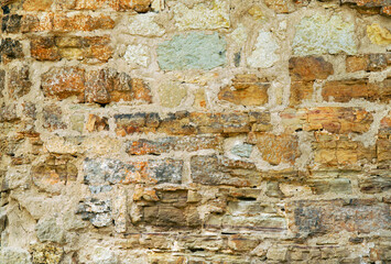 old stone wall of stone of different shapes.