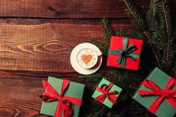 Cup of coffee and heart shape next to gift boxes on wooden table