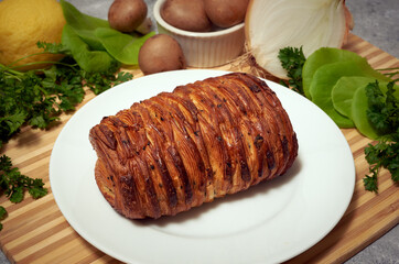 Mushroom croissant on a plate atop a wooden surface with vegetables, mushroom, onions, spinach, parsley and lemon 