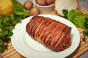 Savory croissant on a plate atop a wooden surface with vegetables, mushroom, onions, spinach, parsley and lemon 