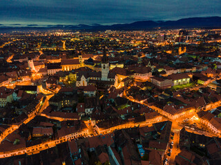 Aerial photography of Sibiu city center shot from a drone at sunset with city lights on. View from above Sibiu, Romania. Landscape photography taken from above Sibiu, Romania.