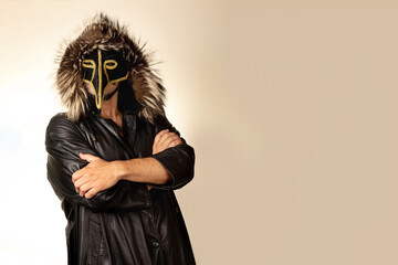 Man with crossed arms and mask on plain background.