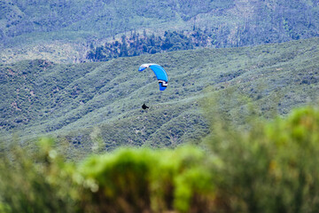 Paragliding Pilot Flying a Paraglider - 468452449