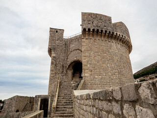 Fototapeta na wymiar Looming ancient stone tower built into wall around city of Dubrovnik, Croatia 