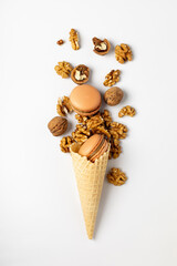 Macaroon cake with nuts in a waffle cone for ice cream on a white background