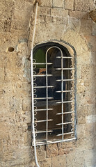 A window in the wall of an old house in ancient Jaffa, closed with decorative lattice made of metal...