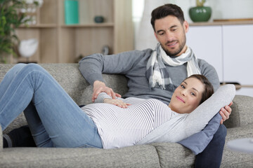 Fototapeta premium young man and pregnant woman lying on sofa