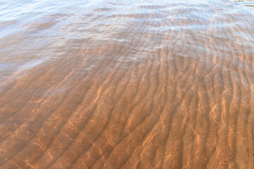Sandy seabed with wavy relief is under shallow water
