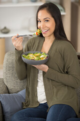 woman sat on the sofa eating a pasta salad