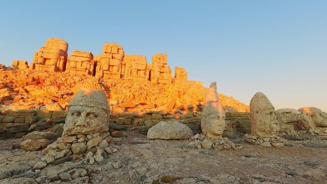 Static view Statues on top of the Nemrut Mountain with tourist silhouettes against sun in Adiyaman, Turkey. 4K Timelapse morning sunset east side Nemrut Dagi