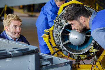 engineering teacher checking airplane engines with his students