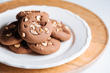 Close up of chocolate cookie with hazelnut and chocolate crumbs positioned on other cookies