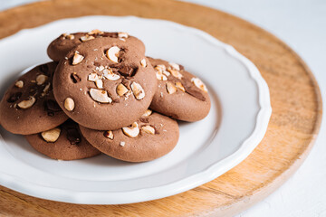 Close up of chocolate cookie with hazelnut and chocolate crumbs positioned on other cookies