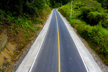 Fototapeta na wymiar A hardened road divided with a yellow line running down a mountain slope