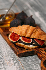 Breakfast with croissants, homemade ricotta cheese, figs, honey and espresso coffee on a rustic serving board on a background top view, vertical composition 