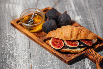 Breakfast with croissants, homemade ricotta cheese, figs, honey and espresso coffee on a rustic serving board on a background top view, vertical composition 