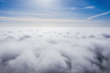 Wind farms sticking out above the clouds, aerial view of distant turbine propellers