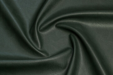 Fototapeta na wymiar green artificial leather with waves and folds on PVC base