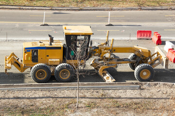 Road grader machine. Two-blade modern motor tractor. Preparing ground for asphalt on a city street. Road construction. Heavy equipment machinery. Heavy-duty vehicles.