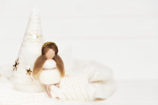 Woolen fairy sitting near the christmas tree with magic wand