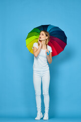 fashionable woman with umbrella rainbow colors posing blue background