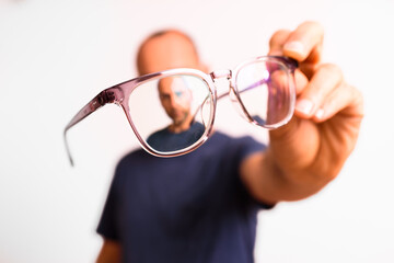 Myopia in mature men is corrected with glasses, a young man holds glasses in his hand.