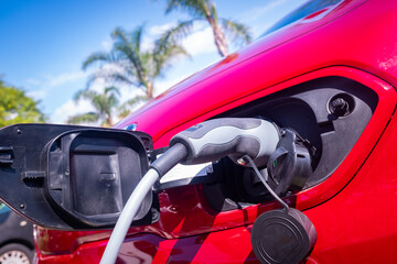 Red car recharging its lithium electric batteries at a free public station.