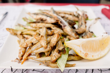 Plate with breaded and fried anchovies with a lemon cut, a typical Spanish appetizer.