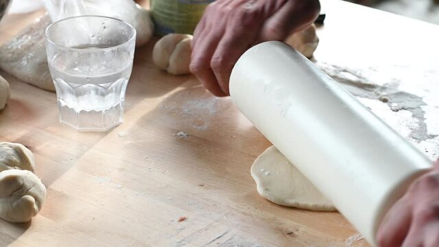 a man in the kitchen at home prepares pasties on the table, rolls out the dough, puts minced meat home meal concept. High quality 4k footage