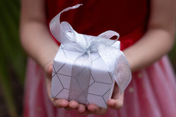 A close-up gift box lies in the hands of the child