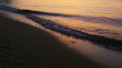 Fototapeta na wymiar Closeup sea waves splashing sandy beach in cold evening sunset dusk slow motion
