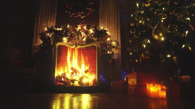Fireplace with burning fire. Christmas and New Year interior decoration. Green tree decorated with toys, gifts, present boxes, flashing garland, illuminated lamps. Cozy Christmas atmosphere. 4K Loop