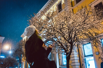 Young woman looking at sparkling snowfall in winter at night