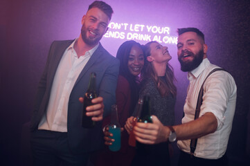 Happy group of friends dancing on a party in a club