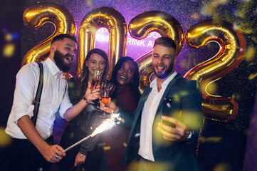 Happy group of friends celebrate New Year's Eve and taking selfie with a smartphone