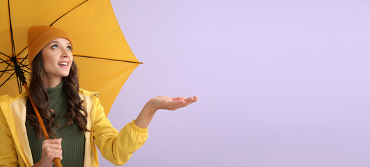 Stylish young woman in autumn clothes and with umbrella on color background with space for text