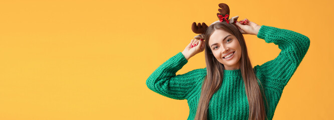 Beautiful young woman with deer horns on yellow background with space for text