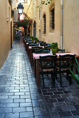 Restaurant chairs and tables set in a narrow street of the city of Chania on the island of Crete