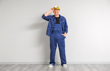 Mature worker with headlamp flashlight near light wall © Pixel-Shot