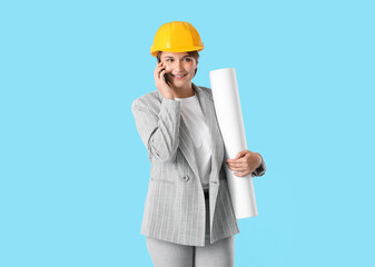 Female industrial engineer with house plan talking by mobile phone on blue background
