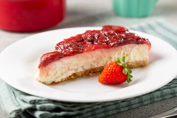 Strawberry glazed cheesecake on white dinnerware on the table.