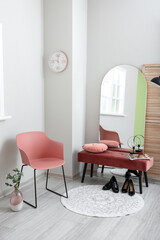 Interior of stylish hallway with big mirror and pink chair