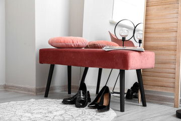Pink ottoman with lamp and female shoes near mirror in hallway