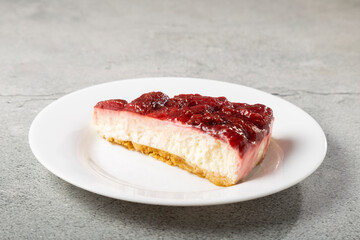 Strawberry glazed cheesecake on white dinnerware on the table.