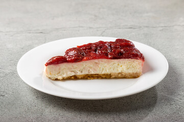 Strawberry glazed cheesecake on white dinnerware on the table.