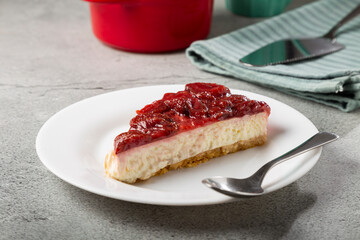 Strawberry glazed cheesecake on white dinnerware on the table.
