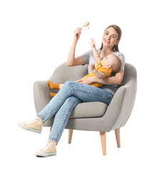 Young mother with little baby and toy sitting in armchair on white background