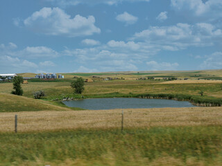 Fototapeta na wymiar Small pond surrounded by greenery along Highway 44 in South Dakota, USA.